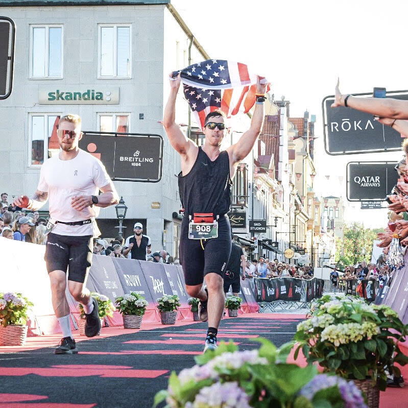 Shane Hixon finishing Ironman Kalmar in Sweden, carrying an American flag